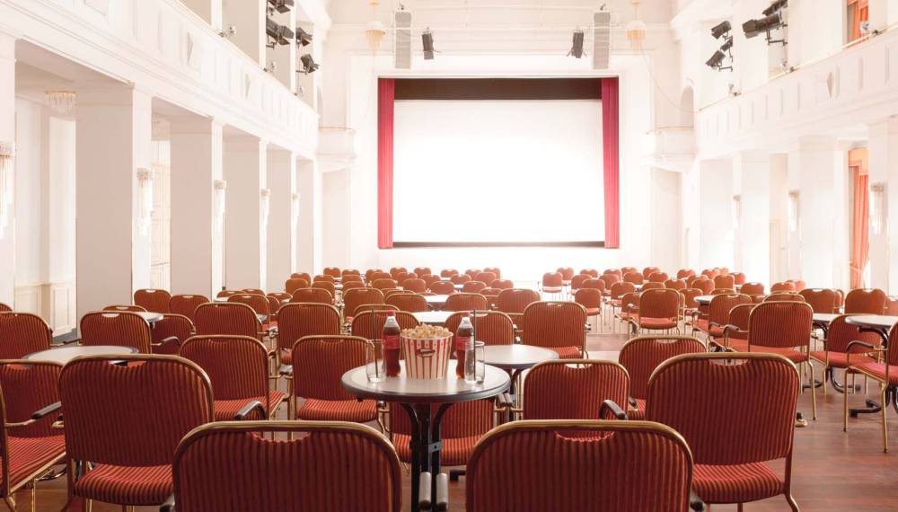 Reihen mit roten Stühlen vor einer großen Kino-Leinwand im Kaiserbädersaal in Heringsdorf auf Usedom.