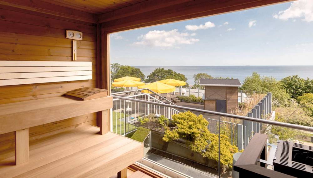 Finnische Meerblicksauna im Hotel Kaiserhof Heringsdorf mit Panoramafenster und Blick auf die Ostsee sowie den Außenbereich des Hotels