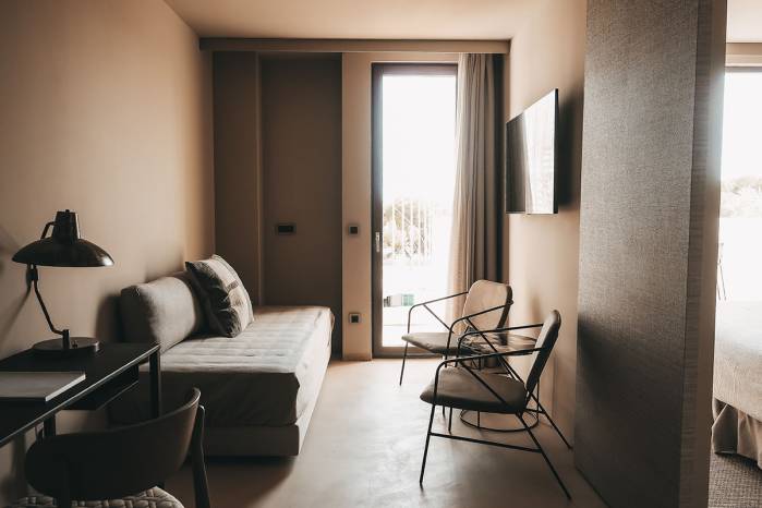 Zona de estar modernamente amueblada en la Suite Lado Campo del Hotel Pies Descalzos con un sofá, dos sillones y vistas a la terraza.