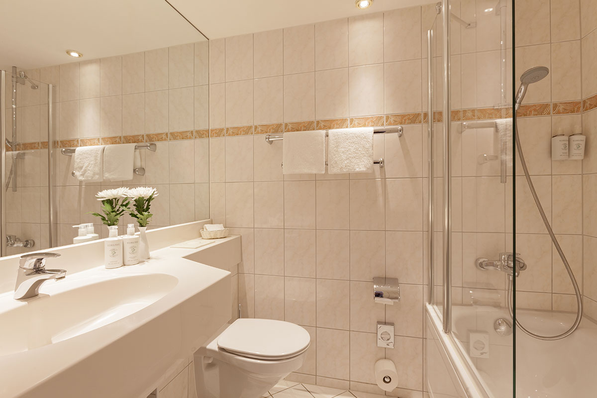 Modern bathroom with shower, bathtub and elegant fittings in the Classic Plus double room with sea view at the Hotel Kaiserhof.