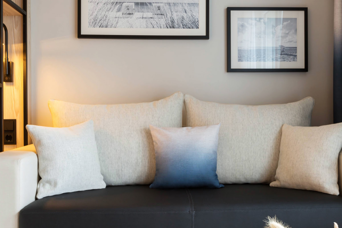 A cozy sofa with several cushions in the deluxe double room with promenade view at the Hotel Kaiserhof Heringsdorf.