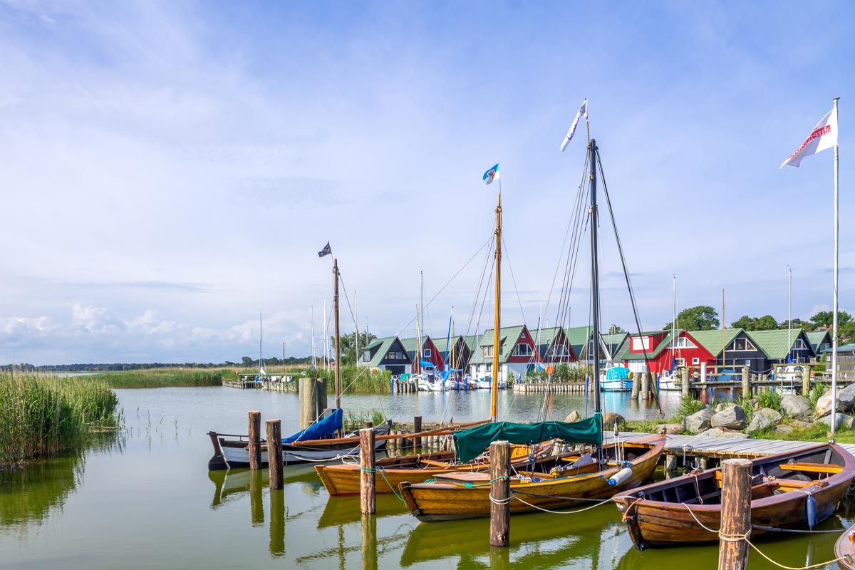 Malerischer Hafen mit Holzstegen, Segelbooten und farbenfrohen Häusern im Urlaub in einer Ferienwohnung in Ahrenshoop.