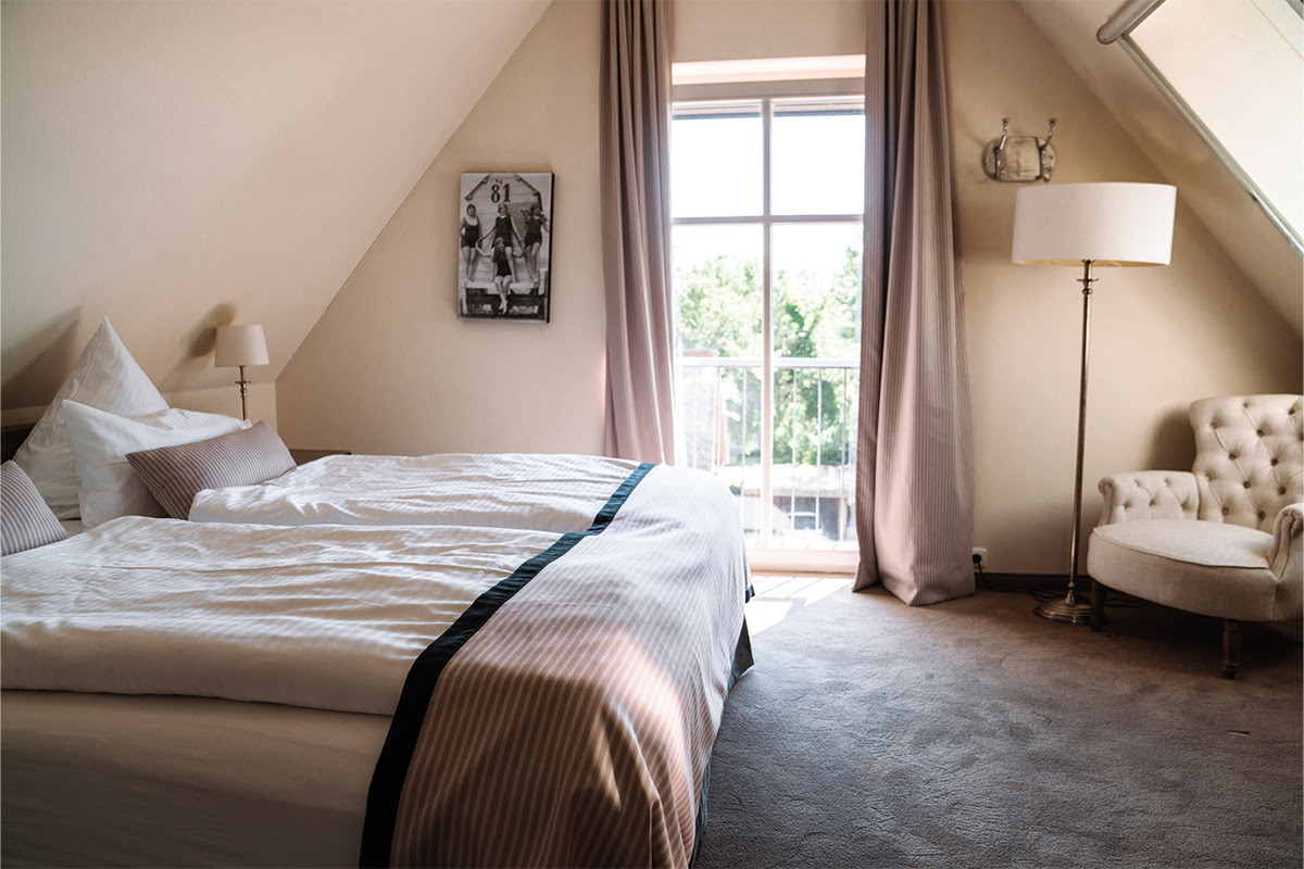 Modern bedroom in the Dünenpark vacation apartment in the Hotel Künstlerquartier Seezeichen with large bed and lake view.