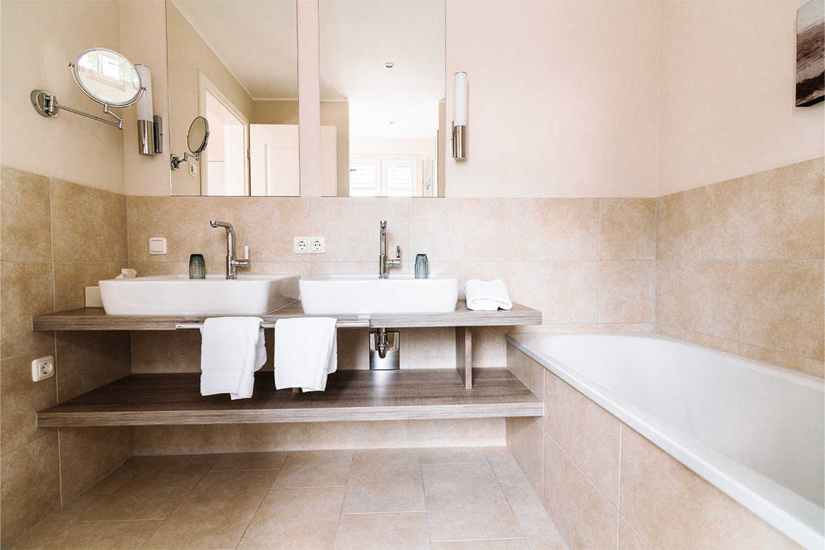 Modern bathroom in the Seepferd vacation apartment with two washbasins and bathtub in the Hotel Künstlerquartier Seezeichen.
