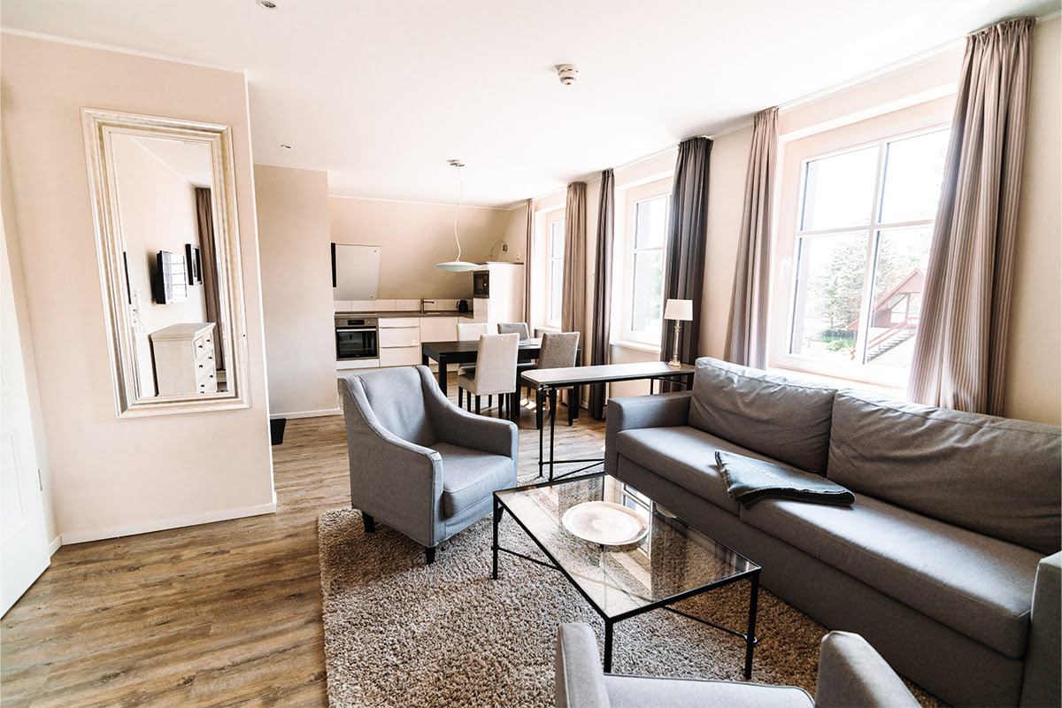 Spacious living area with dining table and lounge furniture in the Seahorse vacation apartment in the dune park on the Baltic Sea.