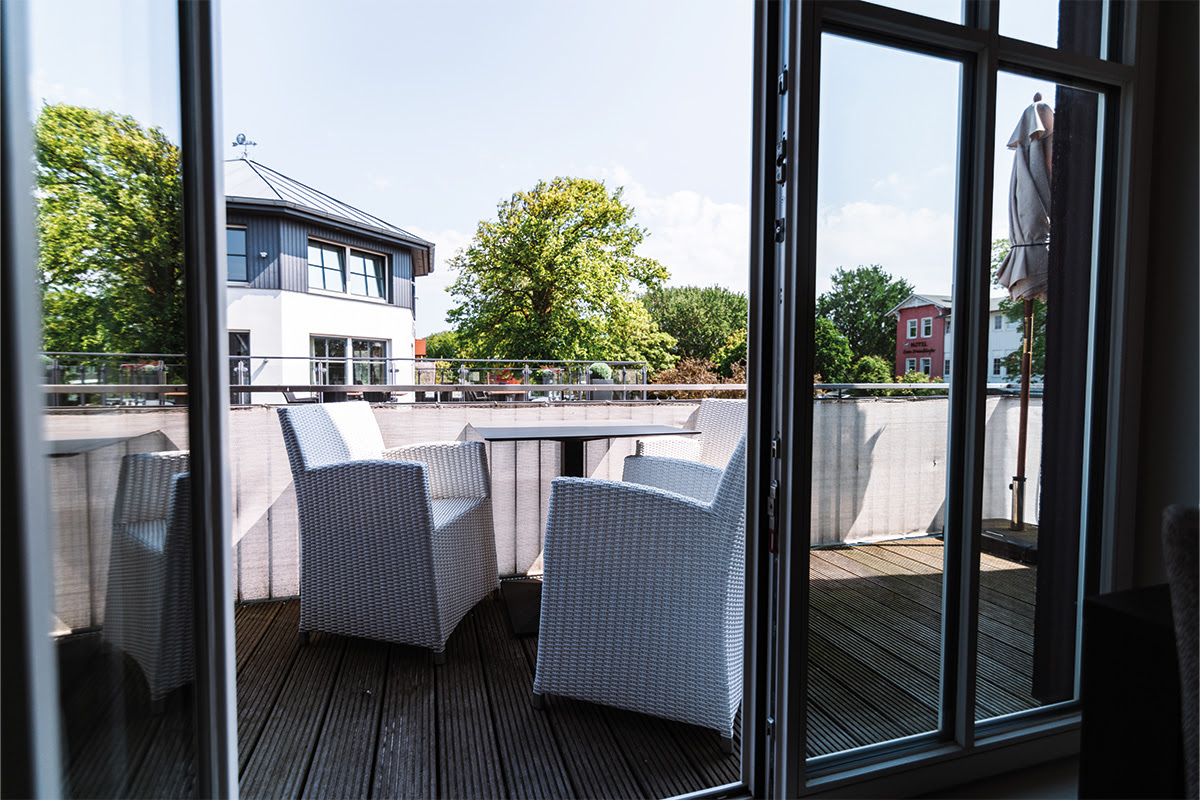 Modern balcony with seating and a view of the greenery in the Strandduene vacation apartment in the Ahrenshoop dune park.