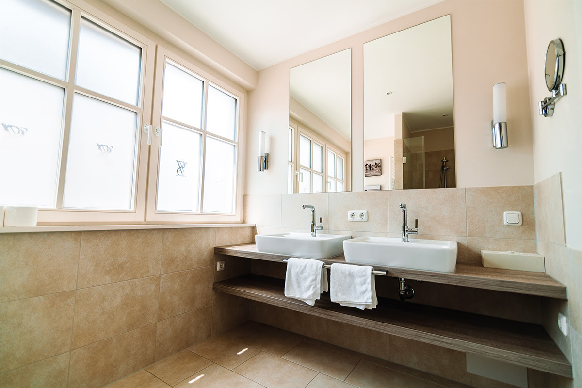 Double washbasin in the bathroom of the Strandmuschel vacation apartment with mirror and towels at Hotel Künstlerquartier Seezeichen.