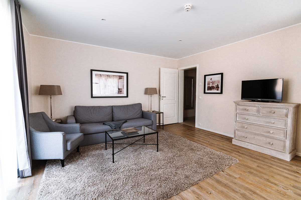 Living area of the Strandmuschel vacation apartment with comfortable seating and TV in the Hotel Künstlerquartier Seezeichen.