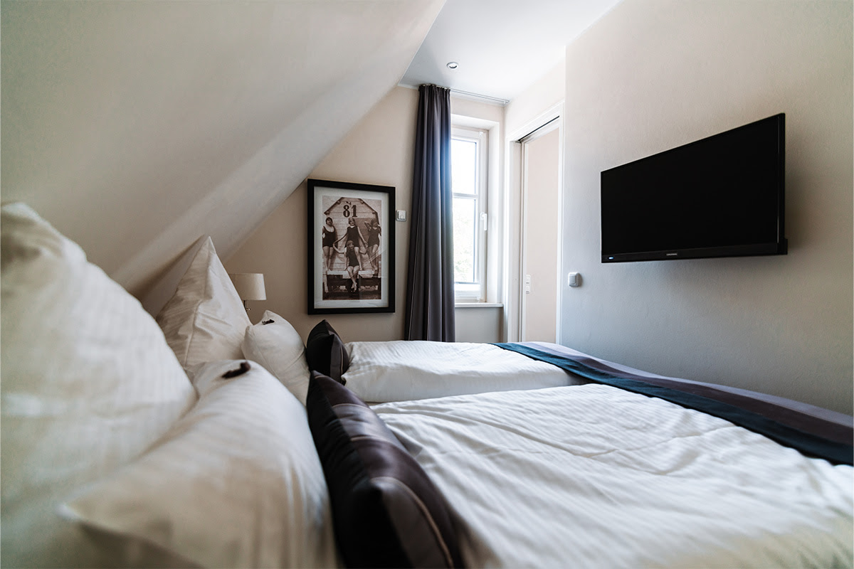 Cozy bedroom with natural light and large bed in the Strandnixe vacation apartment in the Hotel Künstlerquartier Seezeichen.