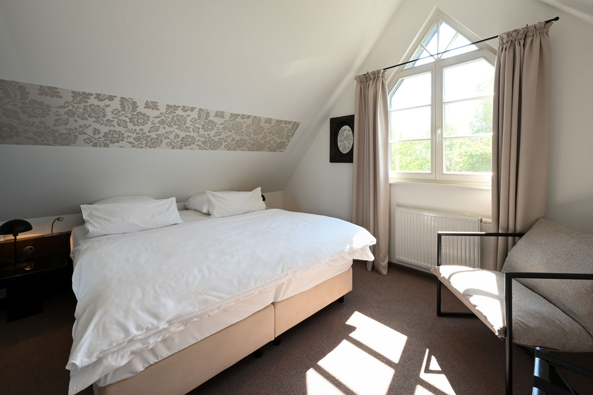 Light-flooded bedroom with large double bed in the Seeadler vacation apartment at the Hotel Künstlerquartier Seezeichen.