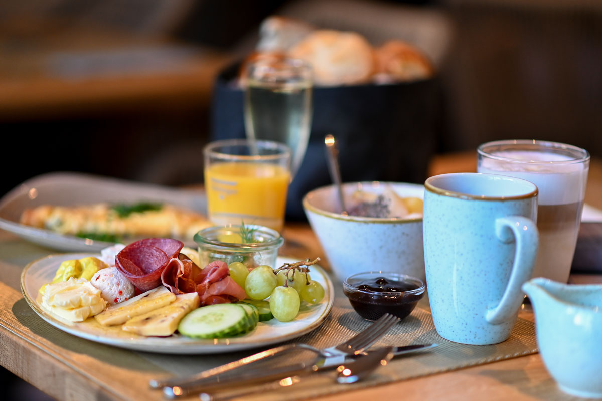 A laid breakfast table with coffee, juice, fresh fruit, cold cuts, cheese and bread rolls at the Vju Hotel on Rügen.