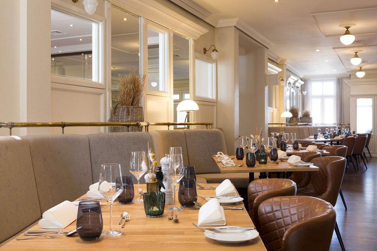 Elegant restaurant Strandläufer with laid tables, stylish lighting and a cozy ambience in the Vju Hotel.