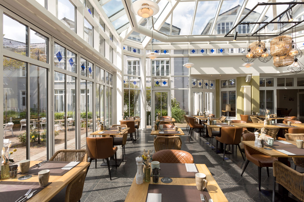 A spacious conservatory with a glass roof, stylish furniture and plenty of natural light at the Vju Hotel on Rügen.