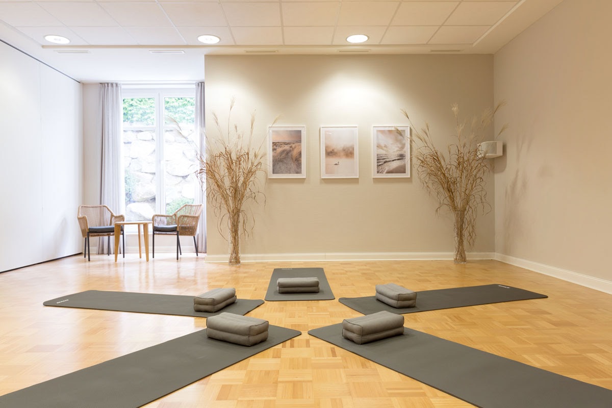 Harmoniously furnished yoga room with mats, cushions and natural light for relaxed exercises at the Vju Hotel.
