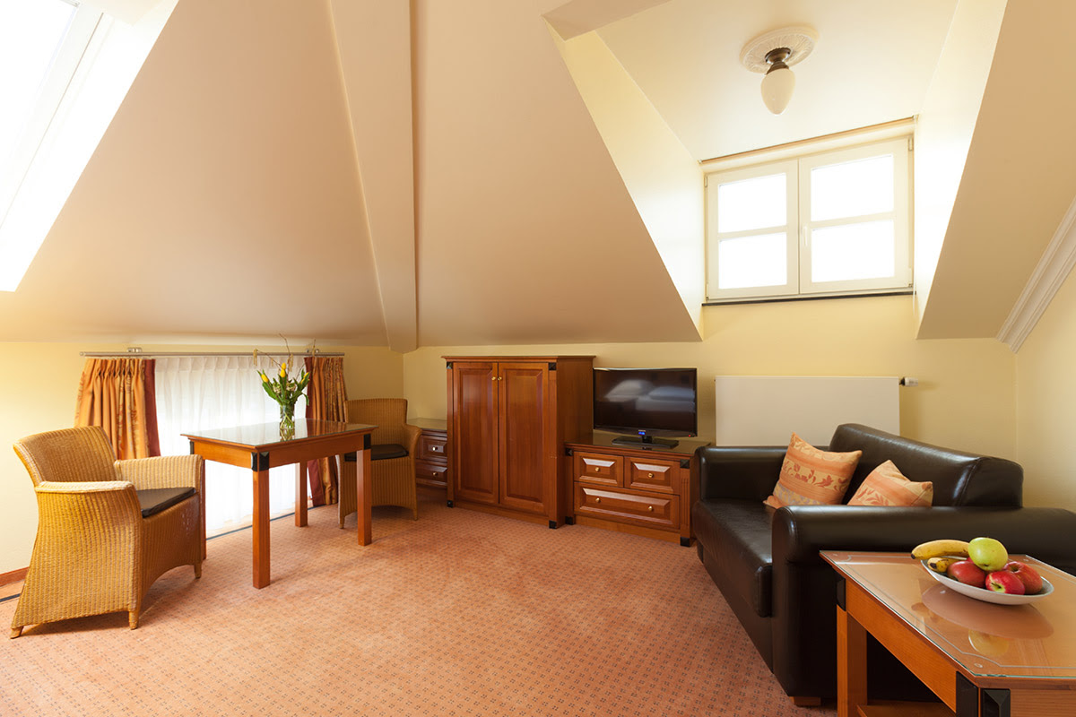 Comfortable seating area with leather sofa, wooden table and TV in the 2-room room in the annexes at the Vju Hotel on Rügen.