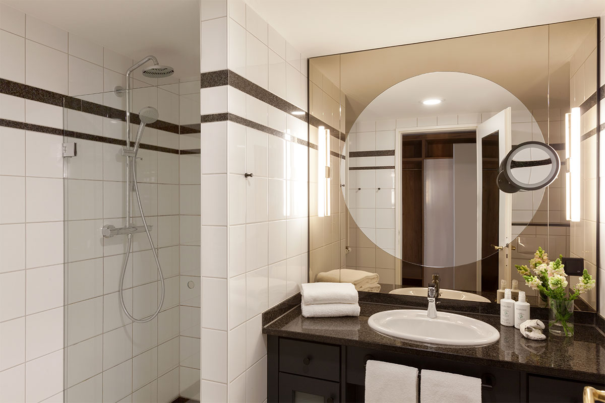 Bright bathroom in Vju Hotel's queen-size single room with large mirrored wall, shower and stylish details.