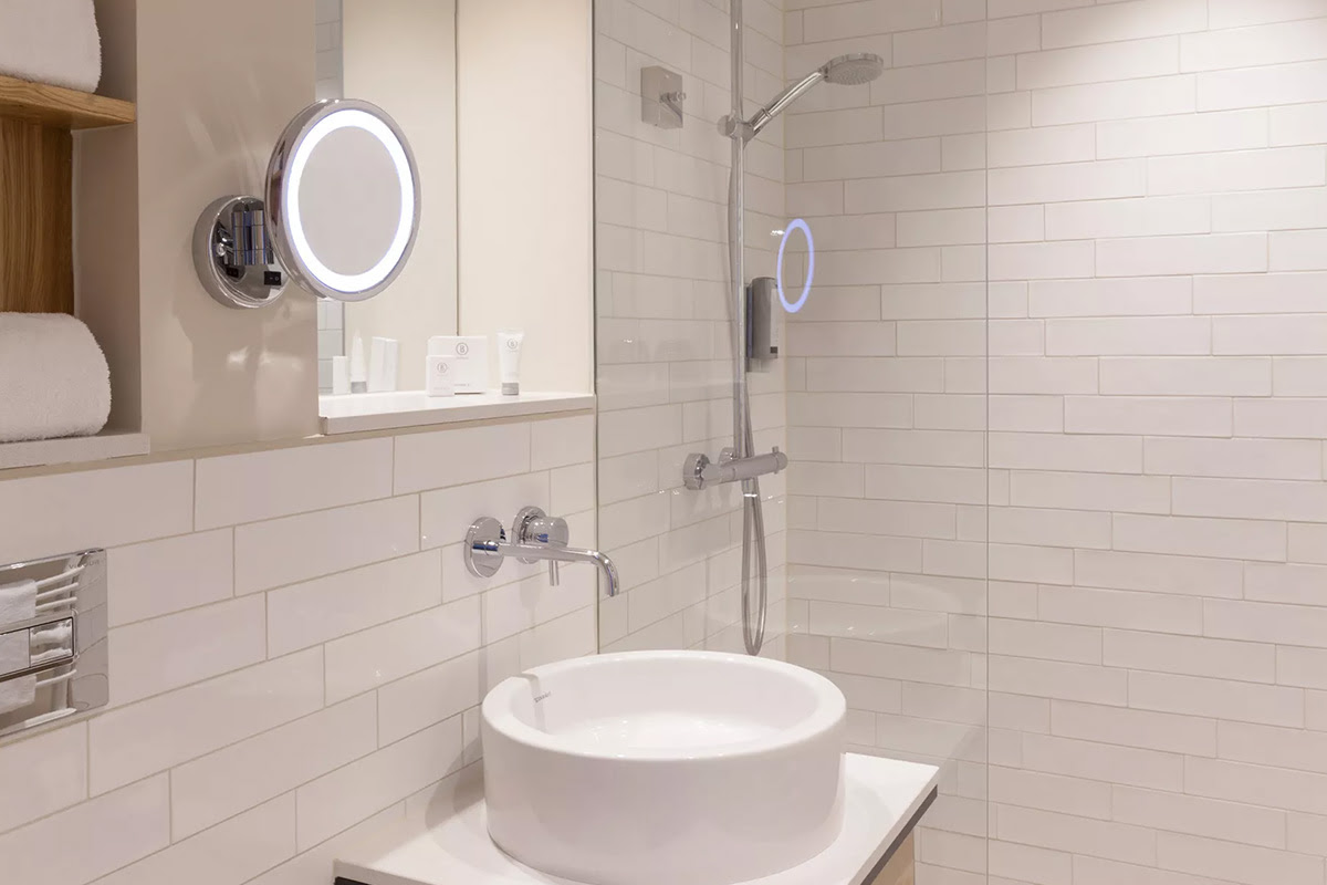 Bright hotel bathroom with large shower, cosmetic mirror in the Muschelsucher room of the Wyn. Strandhotel on Sylt.