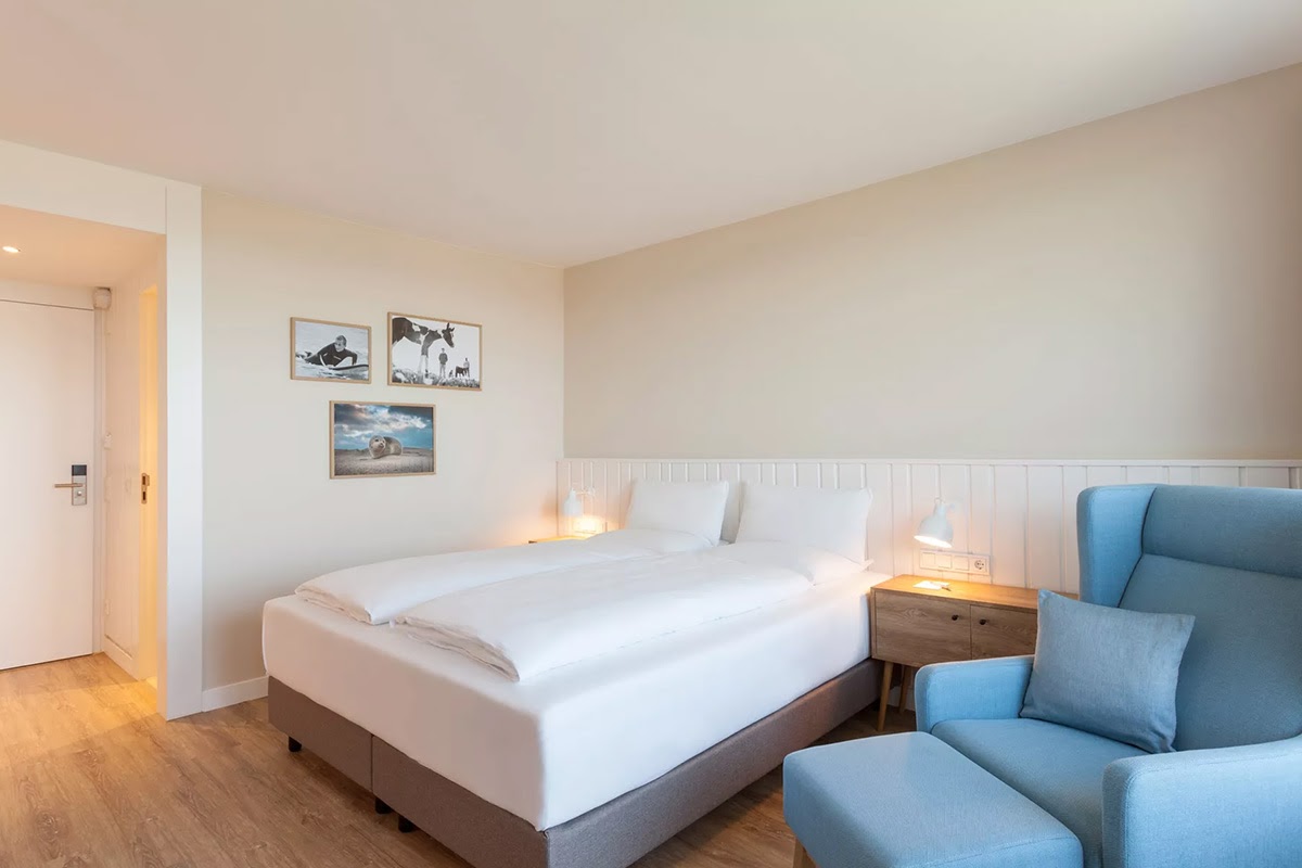 Bright hotel room Muschelsucher in the Wyn. Strandhotel on Sylt with a spacious bed and cozy lighting.