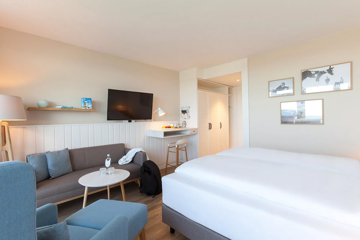 Bright and modern Muschelsucher room with large bed and cozy sitting area in the Wyn. Strandhotel on Sylt.